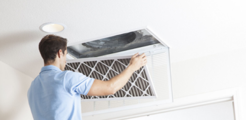 An HVAC technician cleans the air filter of the house