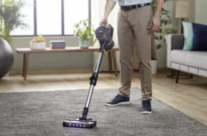 A person who cleans the floor and rag using a vacuum