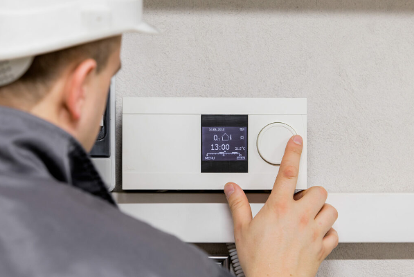 HVAC technician inspects and repairs a thermostat